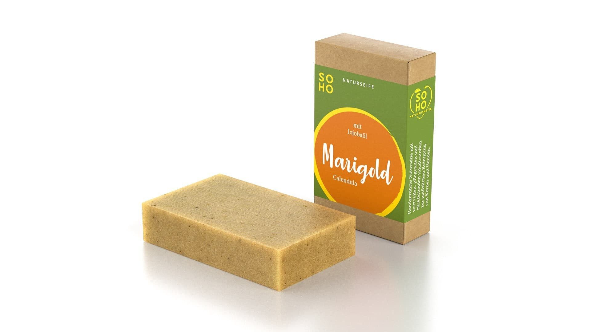Rechteckige Seife neben Verpackung. Verpackung mit grünem Feld und orangefarbenem Kreis mit "Marigold" Schriftzug. "SOHO Naturkosmetik" Logo.