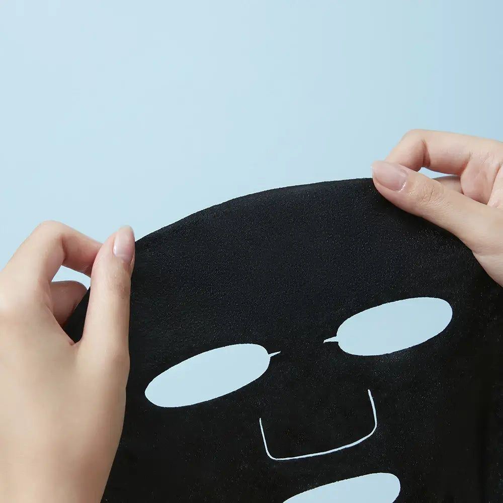 Schwarze Gesichtsmaske mit Augen- und Mundöffnungen, von Händen gehalten.
