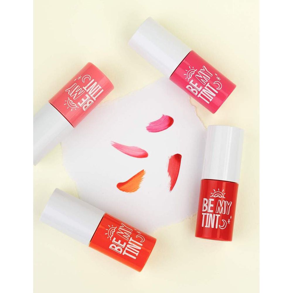 Vier Lippenfarben mit weißen Deckeln. Farbtupfer auf Papier. Verschiedene Farbtöne: rot, rosa, orange.