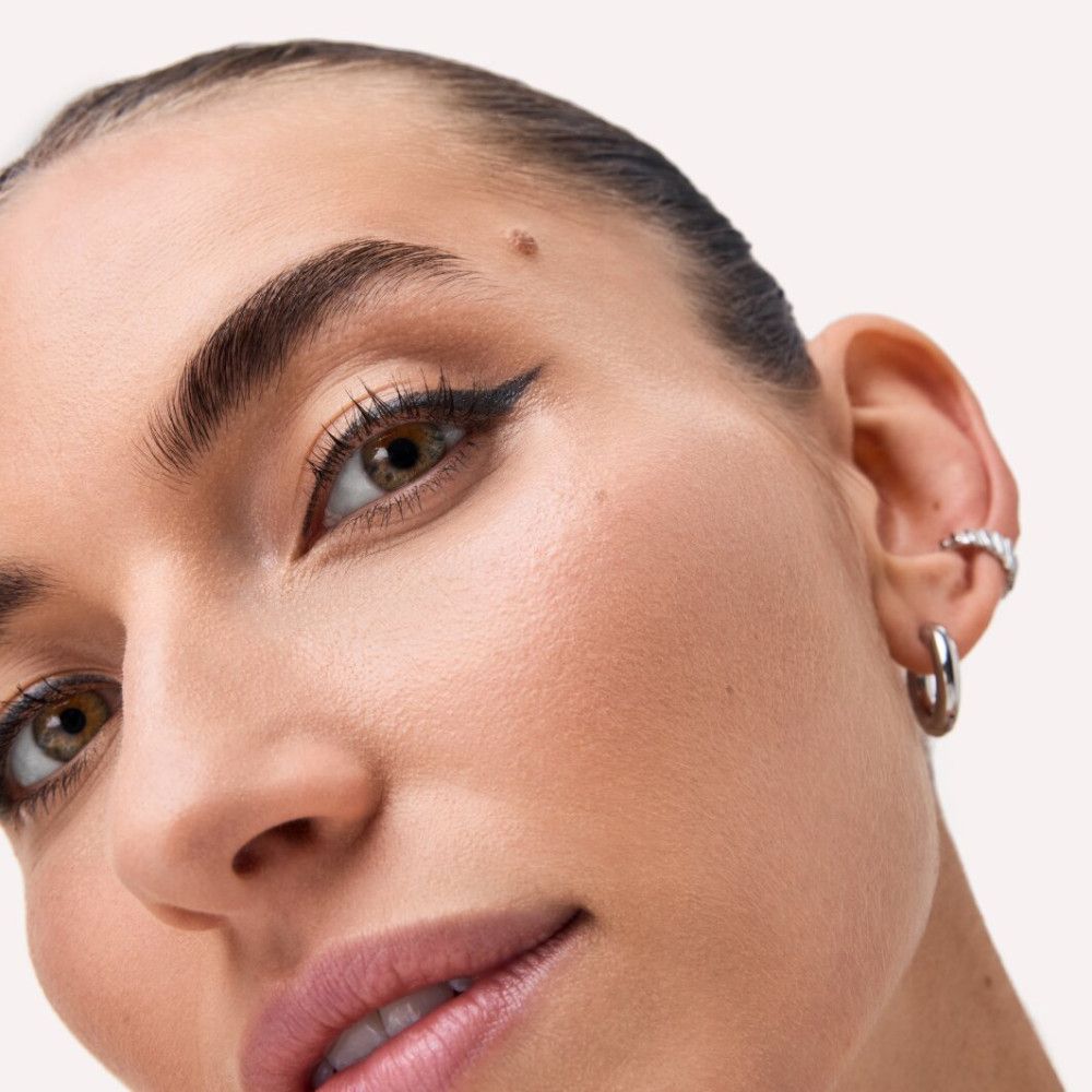 Nahaufnahme eines Gesichts mit Lidstrich. Hautton hell. Ohrringe.