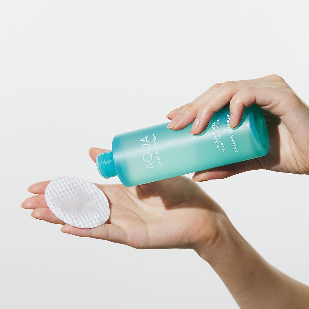Hände halten eine türkisfarbene Flasche und ein Wattepad. Flasche mit "AQUA Super Aqua Max"-Etikett. Marke: NATURE REPUBLIC.