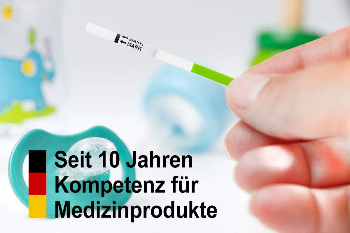 Person hält Ovulationstest-Streifen. Babyartikel im Hintergrund. Text: Seit 10 Jahren Kompetenz für Medizinprodukte.