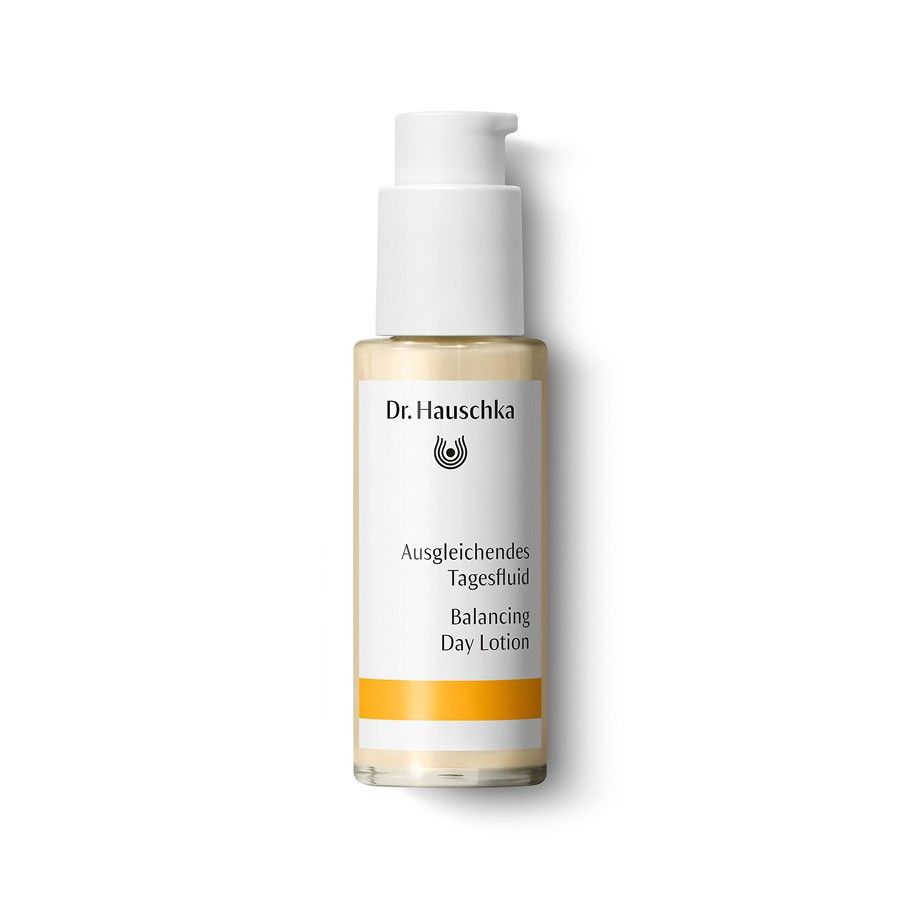 Beige Flasche mit weißem Pumpkopf. Aufschrift: Dr. Hauschka, Ausgleichendes Tagesfluid, Balancing Day Lotion. Gelber Streifen.