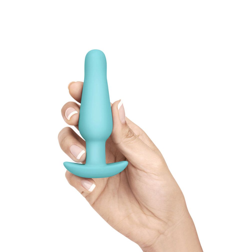 Türkisfarbener Analplug in einer Hand gehalten. Kegelförmig mit breiter Basis.