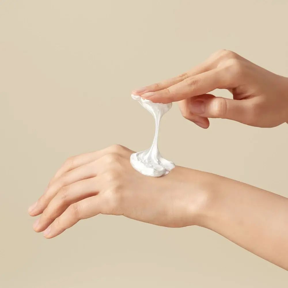 Hände mit weißem Reinigungsschaum auf der Handfläche.