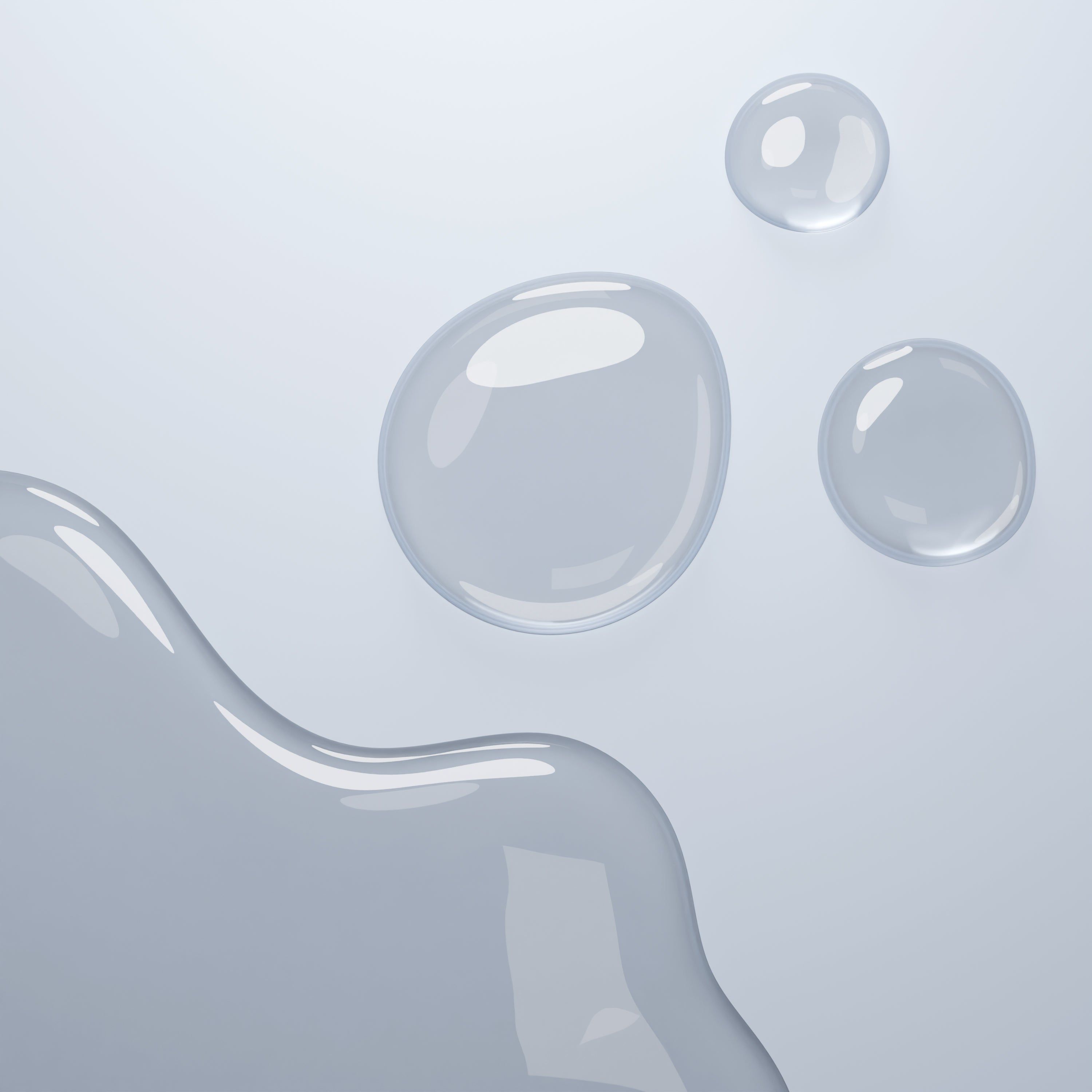 Drei Tropfen Flüssigkeit auf einer hellen Oberfläche. Ein Tropfen ist größer als die anderen.