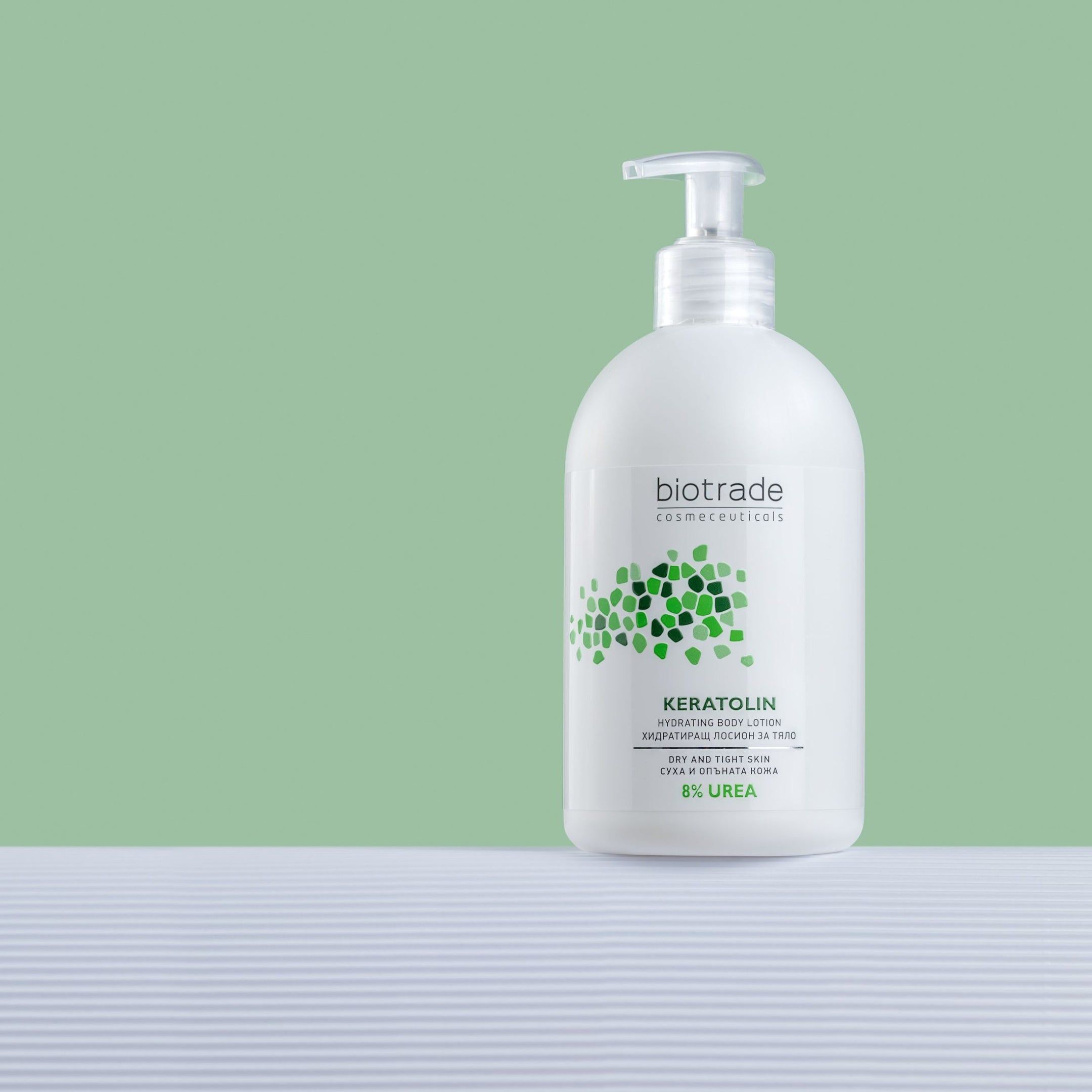 Weiße Flasche mit Spender. Biotrade Keratolin Body, 8% Urea. Auf weißem Untergrund vor grünem Hintergrund.