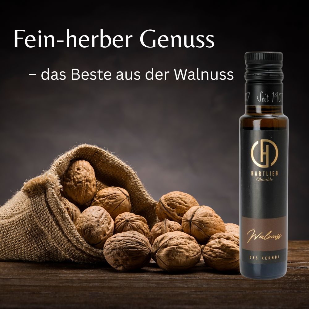 Glasflasche mit "Hartlieb" und "Walnuss" neben Walnüssen in einem Sack auf Holz. Text: Fein-herber Genuss.