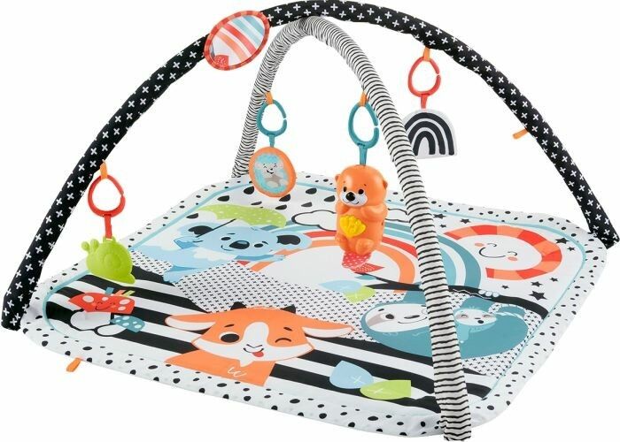 Spieldecke mit Spielbogen. Schwarz-weißes Muster, bunte Spielzeuge hängen am Bogen.