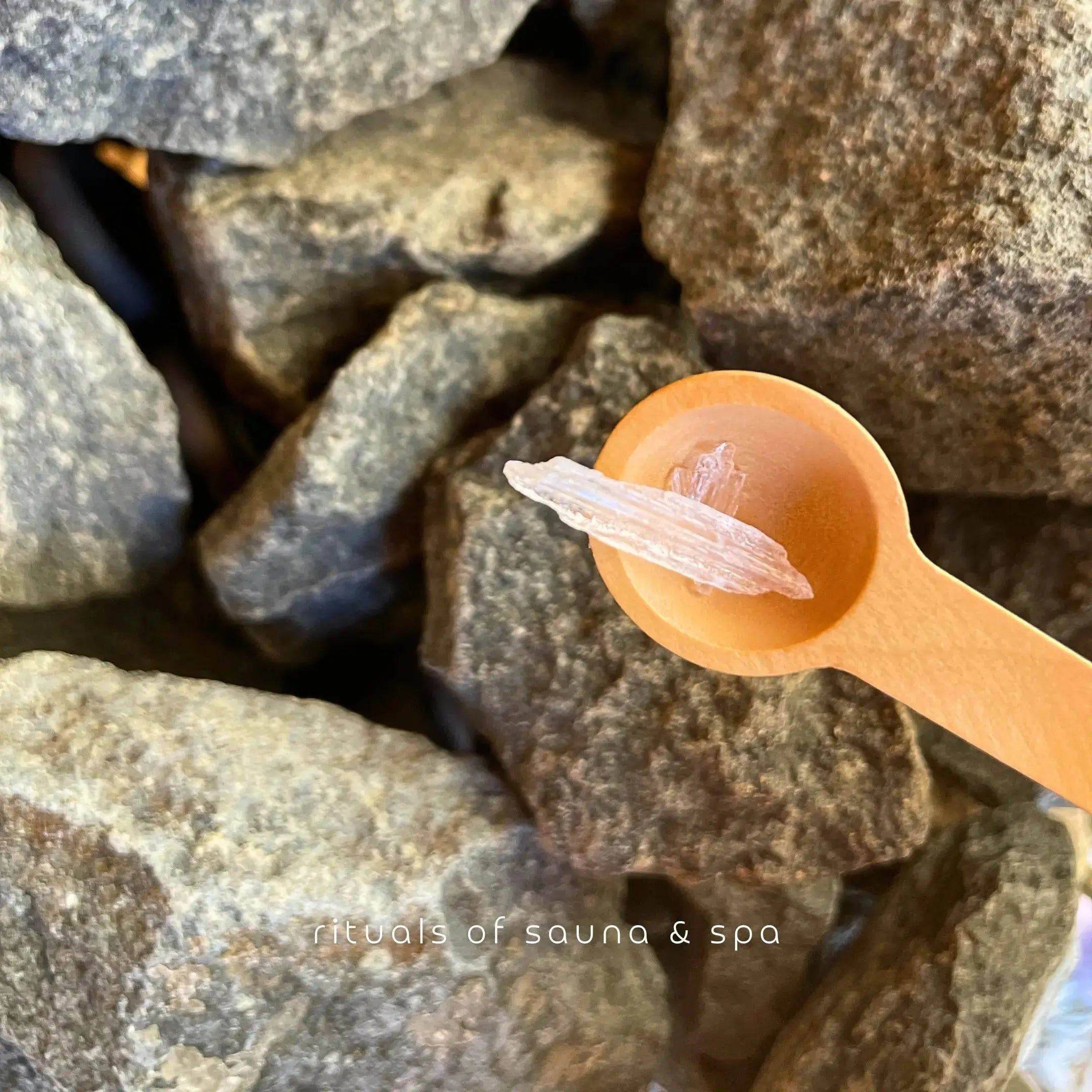 Holzlöffel mit Mentholkristallen auf Steinen. Hintergrund: Saunasteine.