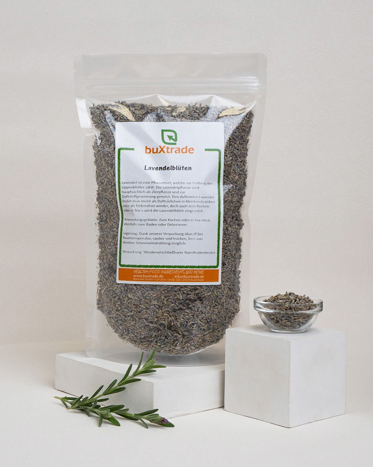 Transparente Tüte mit Lavendelblüten, daneben eine kleine Glasschale mit Blüten. Auf einem Podest.