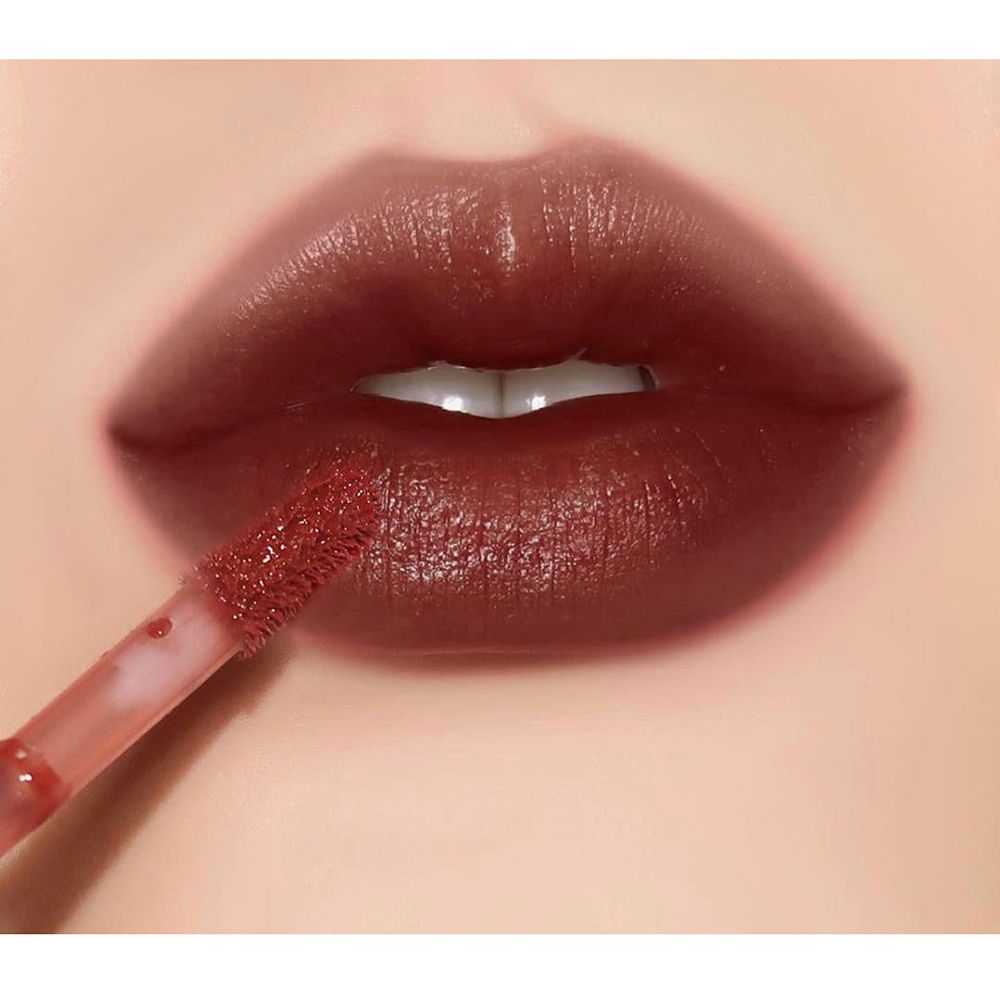 Nahaufnahme von Lippen mit braunem Lipgloss. Applikator sichtbar. Lippen sind glänzend.