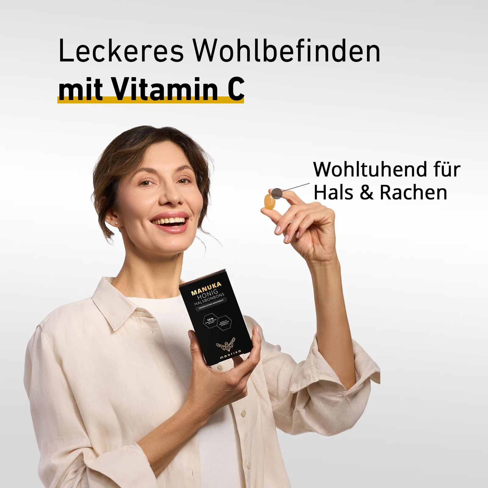 Frau hält eine Packung "MANUKA HONIG HALSBONBONS" und ein Bonbon. Text: Wohltuend für Hals & Rachen. Leckeres Wohlbefinden mit Vitamin C.