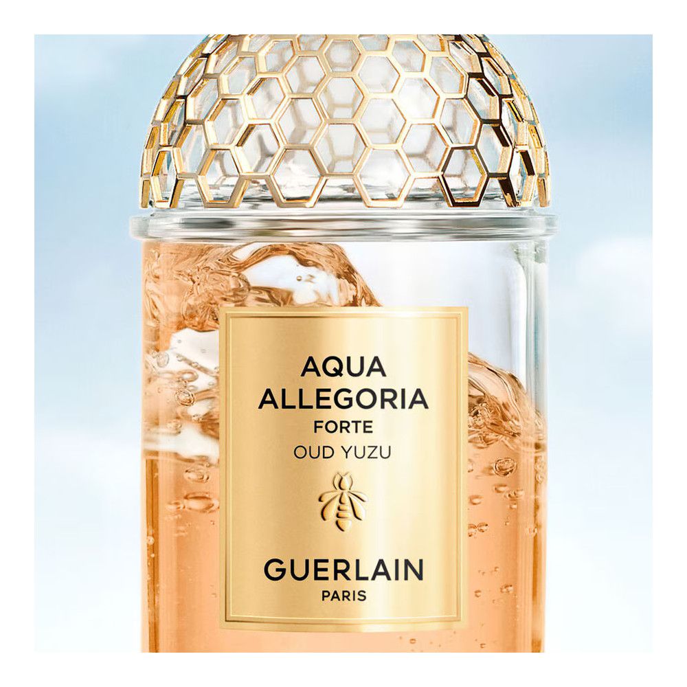 Glasflakon mit goldfarbenem Etikett. Text: AQUA ALLEGORIA FORTE OUD YUZU, Guerlain. Goldfarbenes Wabenmuster auf dem Deckel.