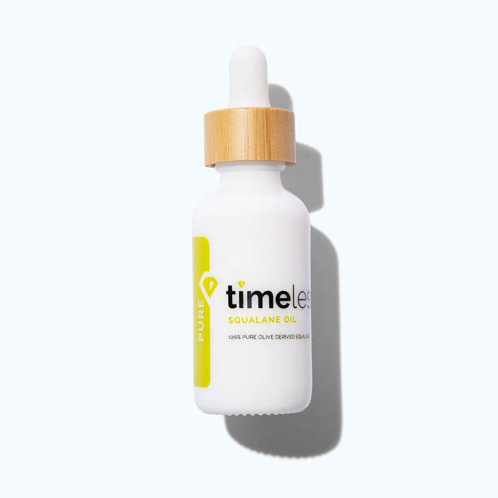Weiße Flasche mit Pipette und Holzverschluss. Aufschrift: TIMELESS Squalane Oil. Gelber Aufkleber mit "PURE".
