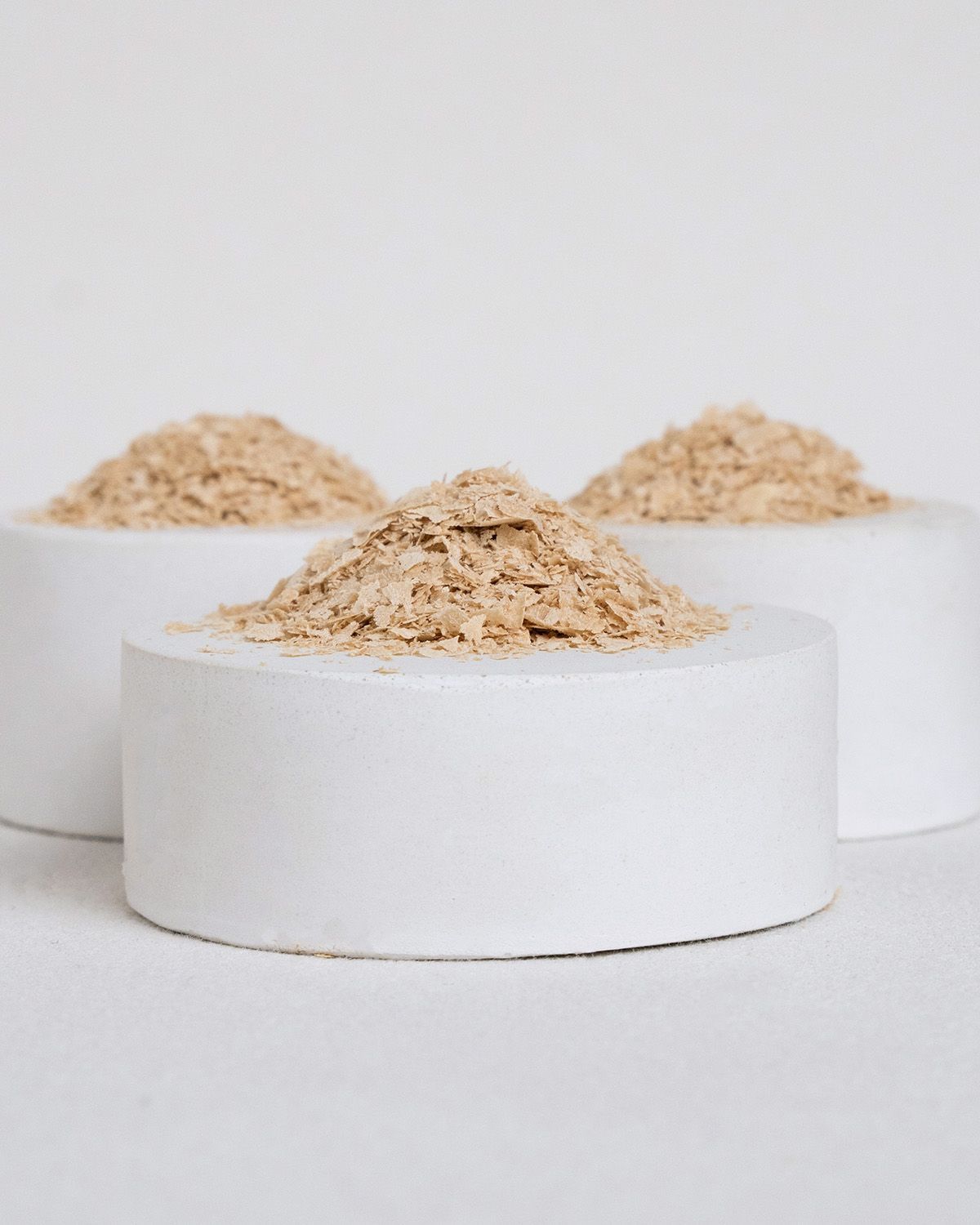 Three white cylindrical containers filled with buXtrade Hefeflocken.