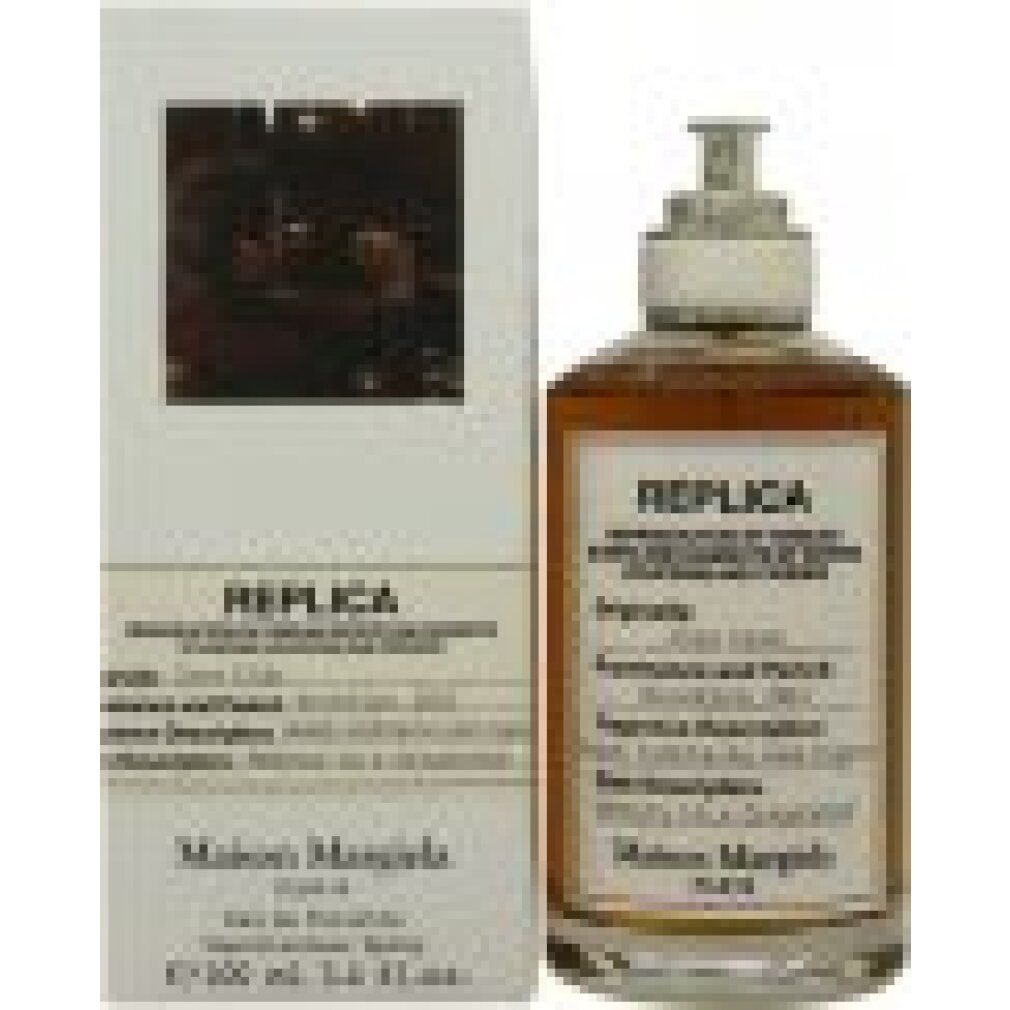 Parfümflakon neben weißer Verpackung. Flakon mit gelblicher Flüssigkeit, Etikett: Replica, Jazz Club, Maison Margiela.