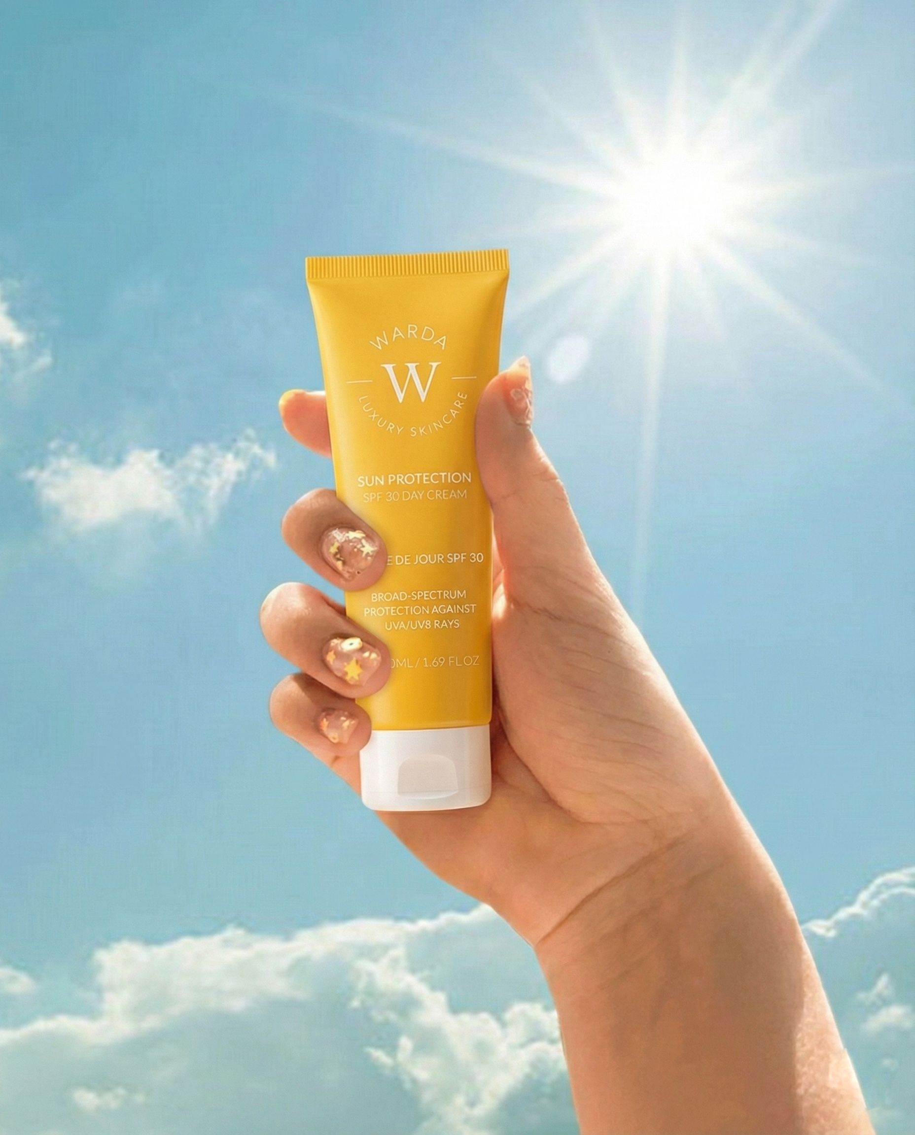 Gelbe Tube in Hand gehalten, vor blauem Himmel und Sonne. Aufschrift: Sun Protection SPF 30 Day Cream. Marke: Warda.