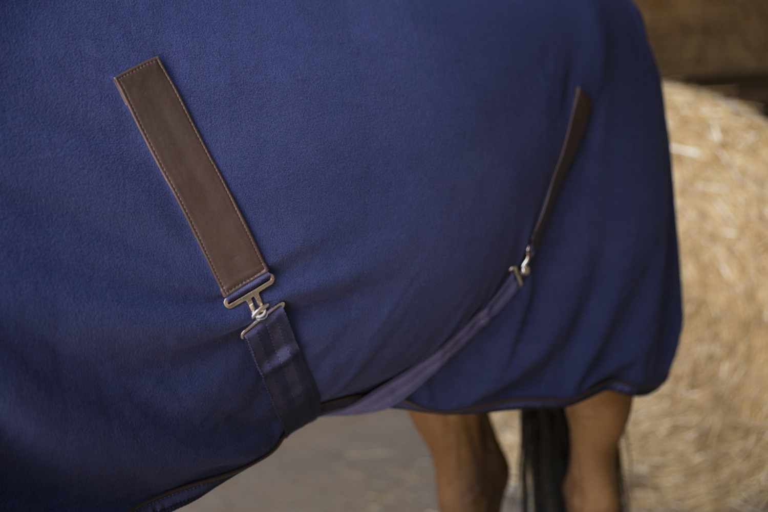 Blaue Fleecedecke mit braunen Lederriemen und Schnallen. Detailaufnahme.