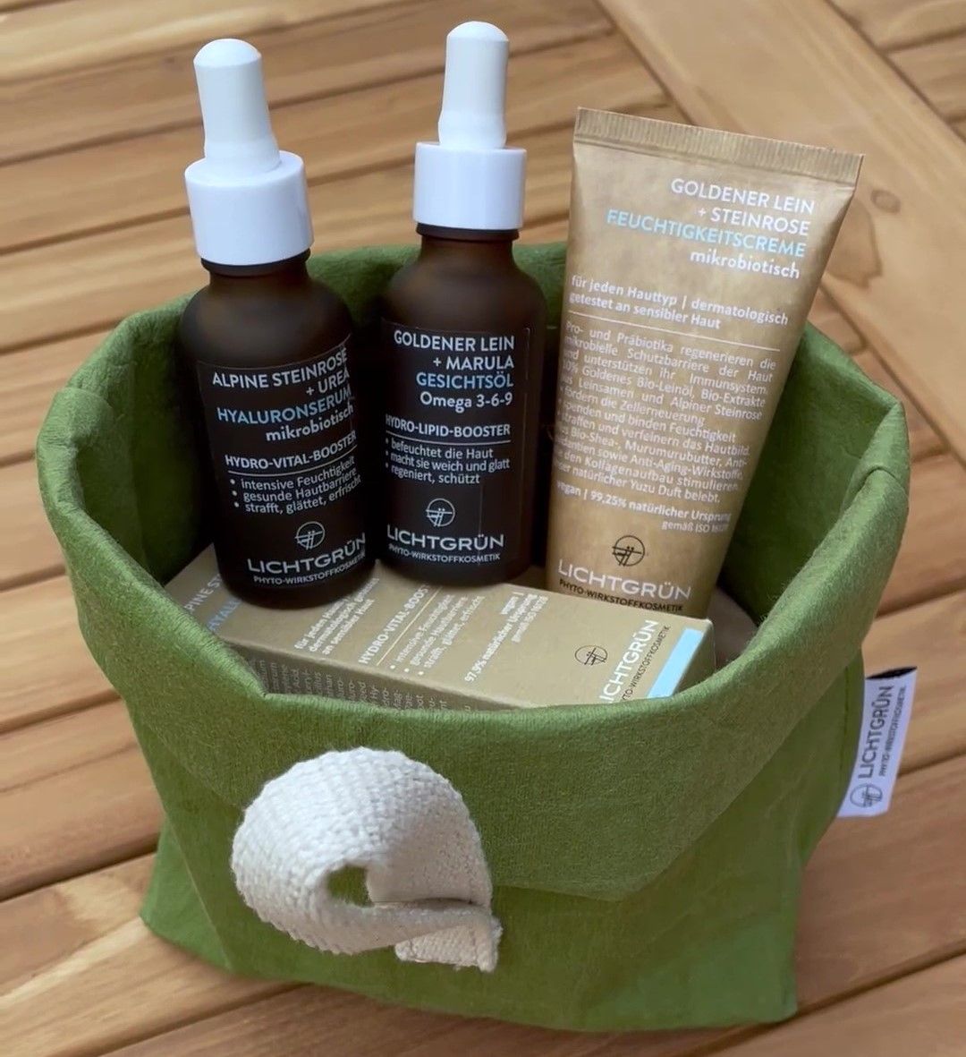 Grüner Behälter mit Produkten, darunter zwei Flaschen und eine Tube. Enthält auch eine Produktverpackung und das Logo LICHTGRÜN®.