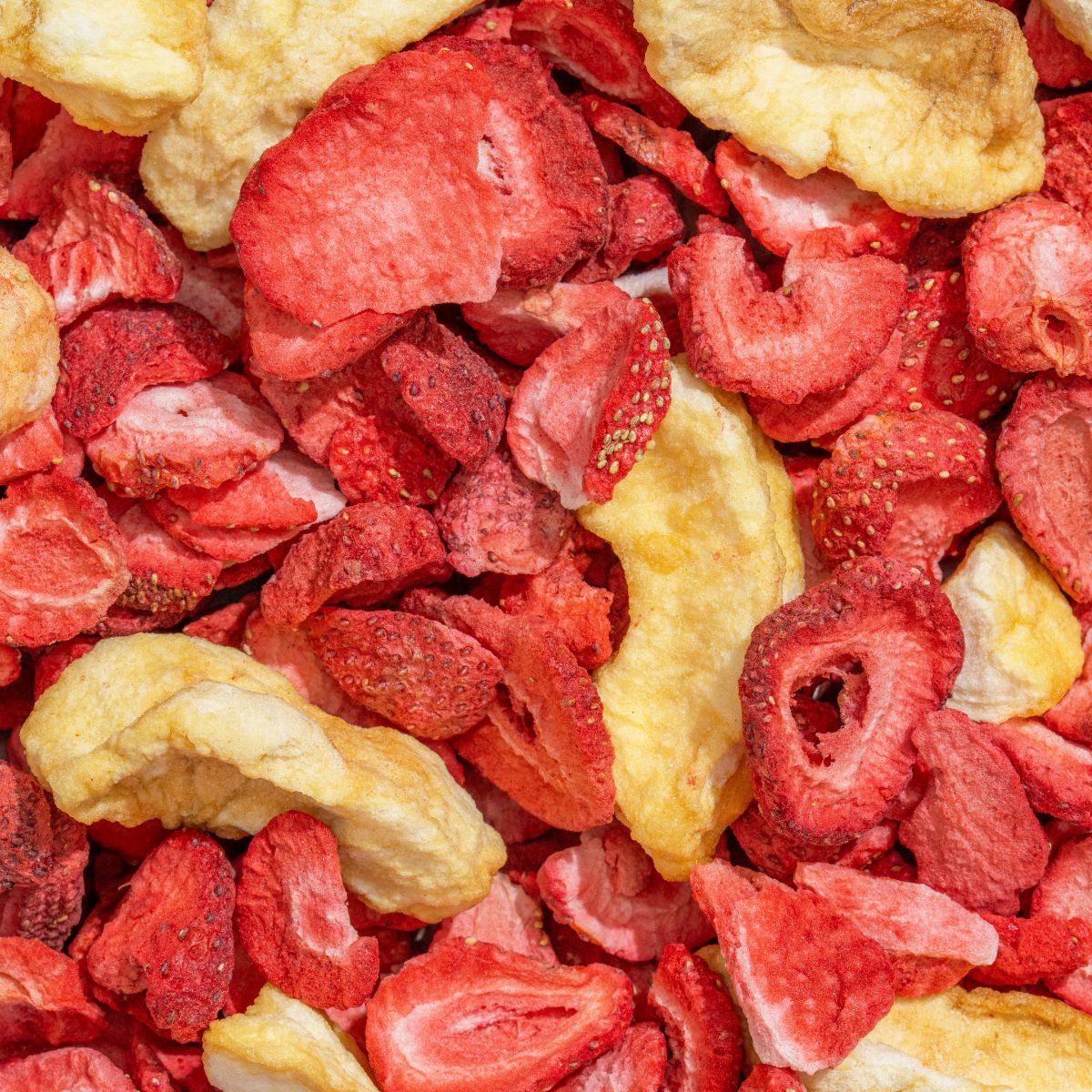 Nahaufnahme von gefriergetrockneten Erdbeeren und Äpfeln. Rote und gelbe Fruchtstücke.