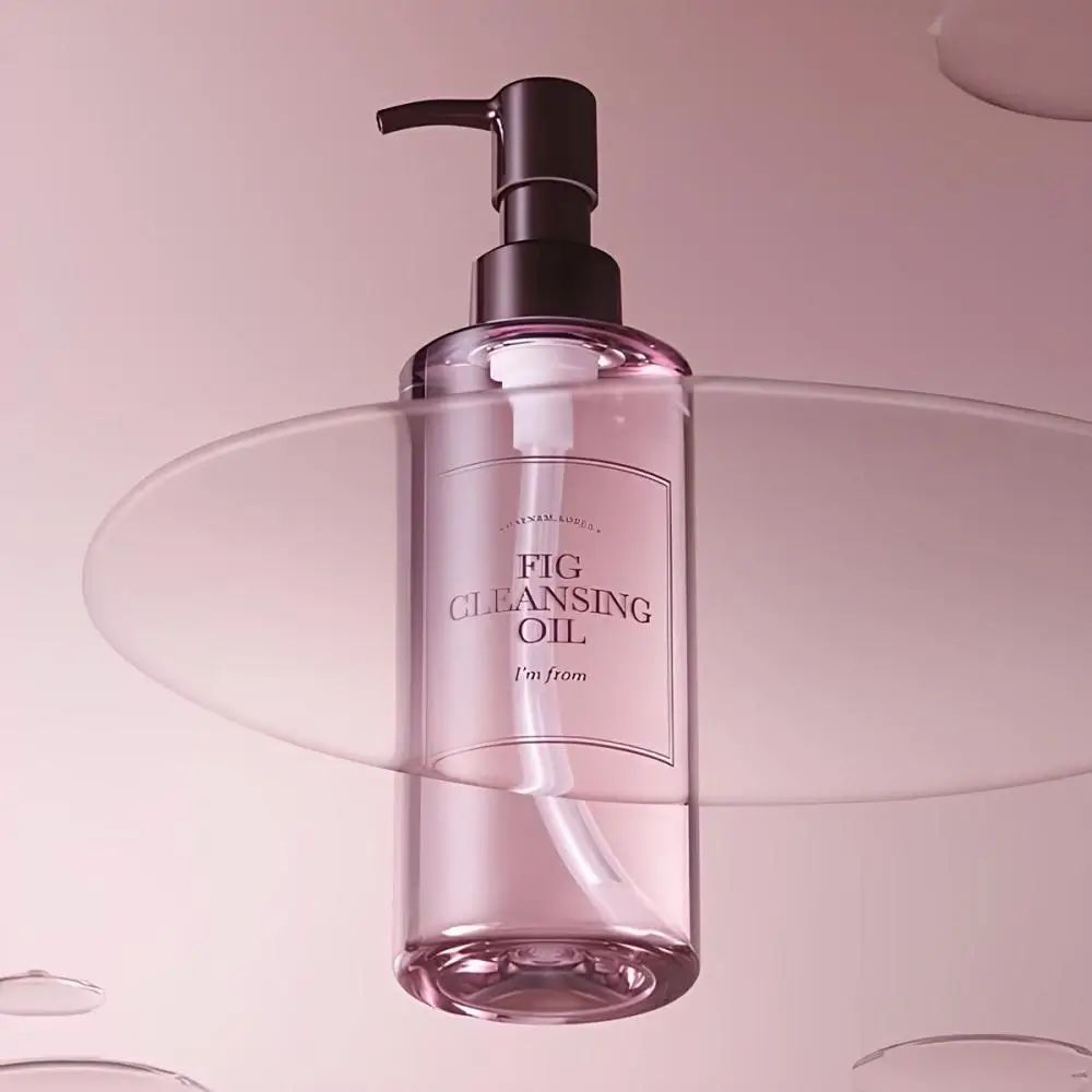 Rosa Flasche mit Pumpe, platziert auf einer transparenten Oberfläche. Etikett "FIG CLEANSING OIL".