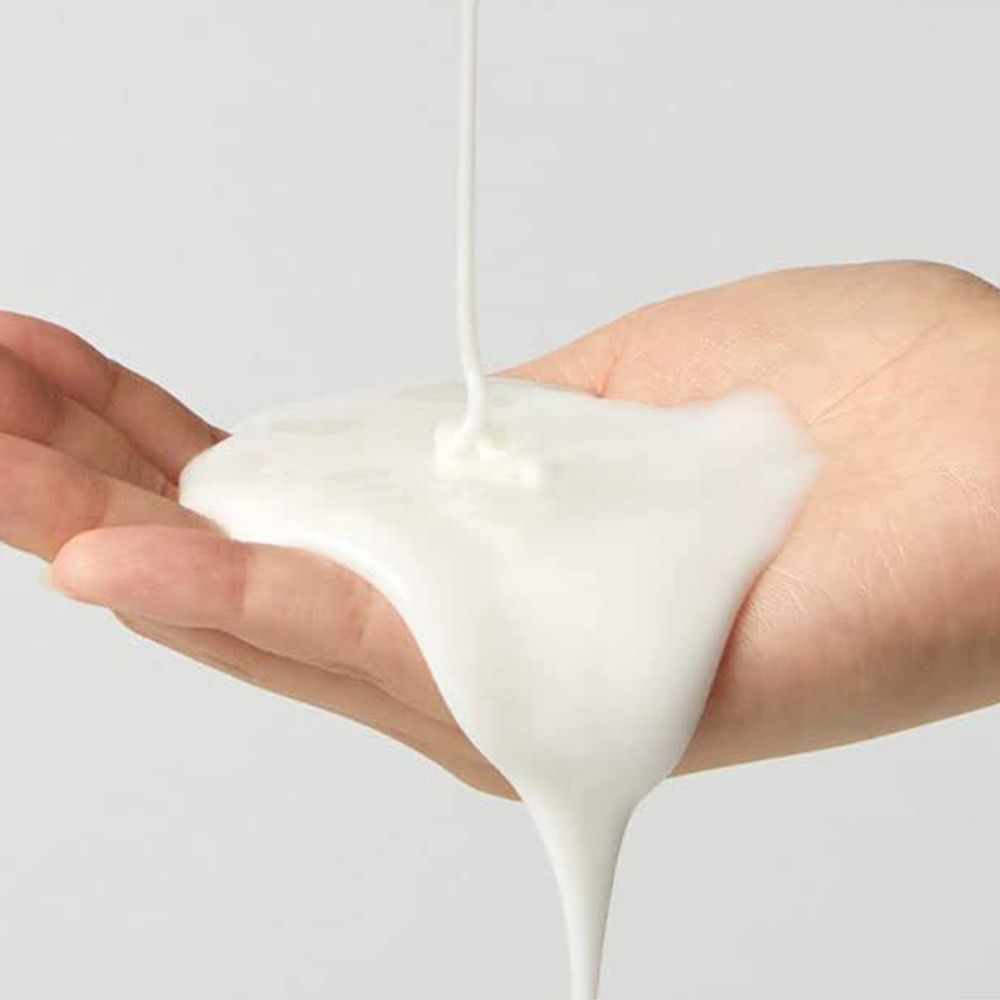 Weiße Maskencreme fließt auf eine offene Hand.