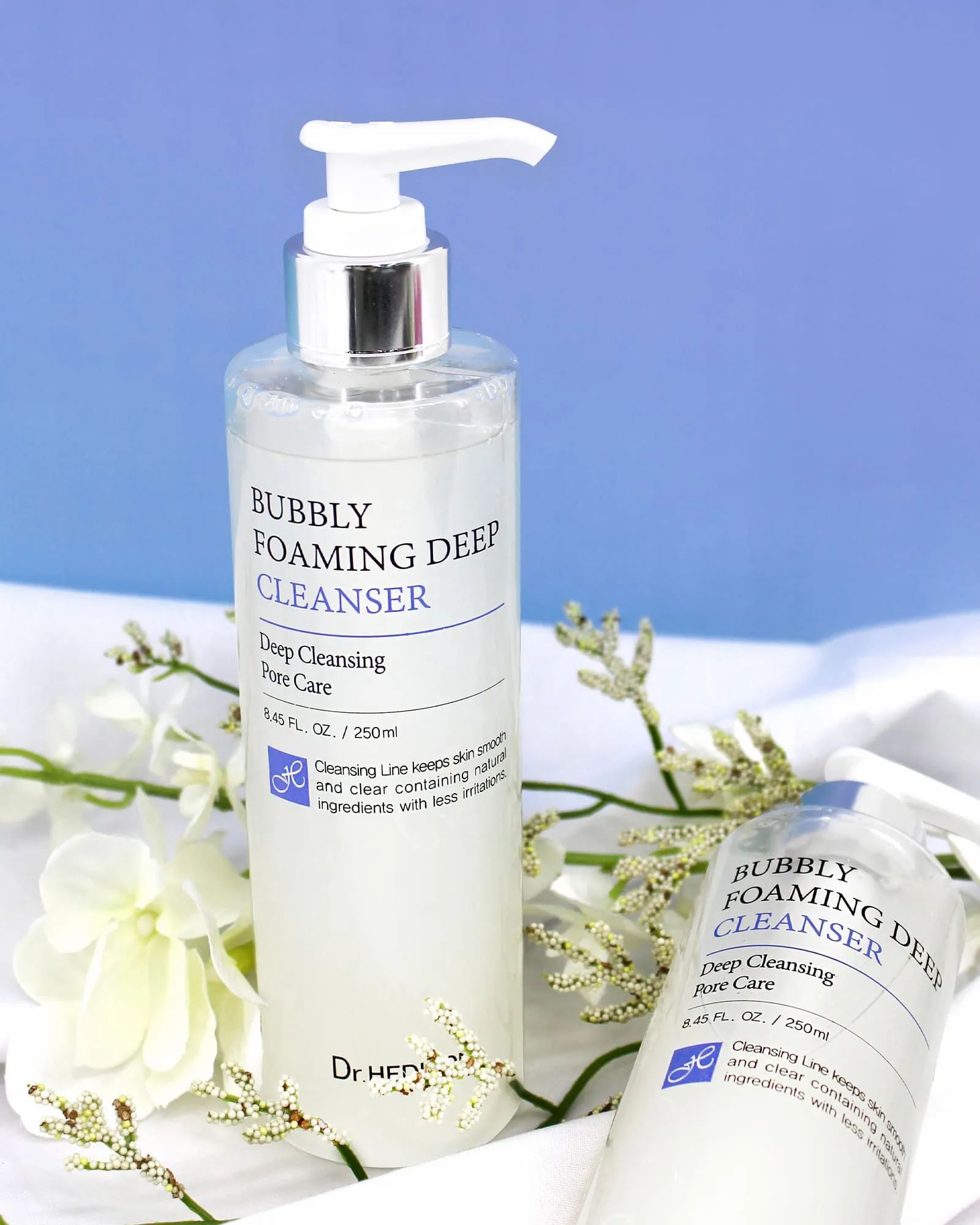 Zwei Flaschen mit Pumpe. Aufschrift: Bubbly Foaming Deep Cleanser. Marke: Dr. Hedison. Auf weißem Stoff.
