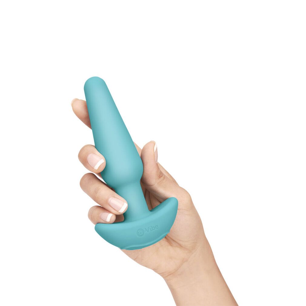 Türkisfarbener Analplug in einer Hand gehalten. Kegelförmig mit breiter Basis.
