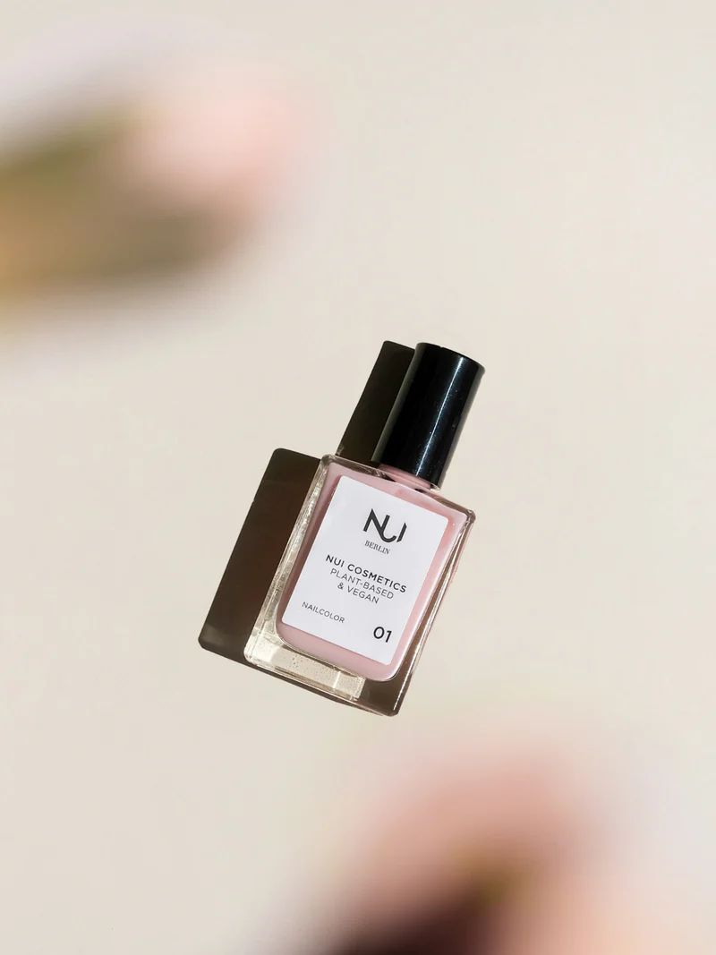 NUI Cosmetics Nagellack Rosé, schräg von oben fotografiert. Rechteckige Glasflasche mit schwarzem Deckel. Etikett mit Logo und Produktinformationen.