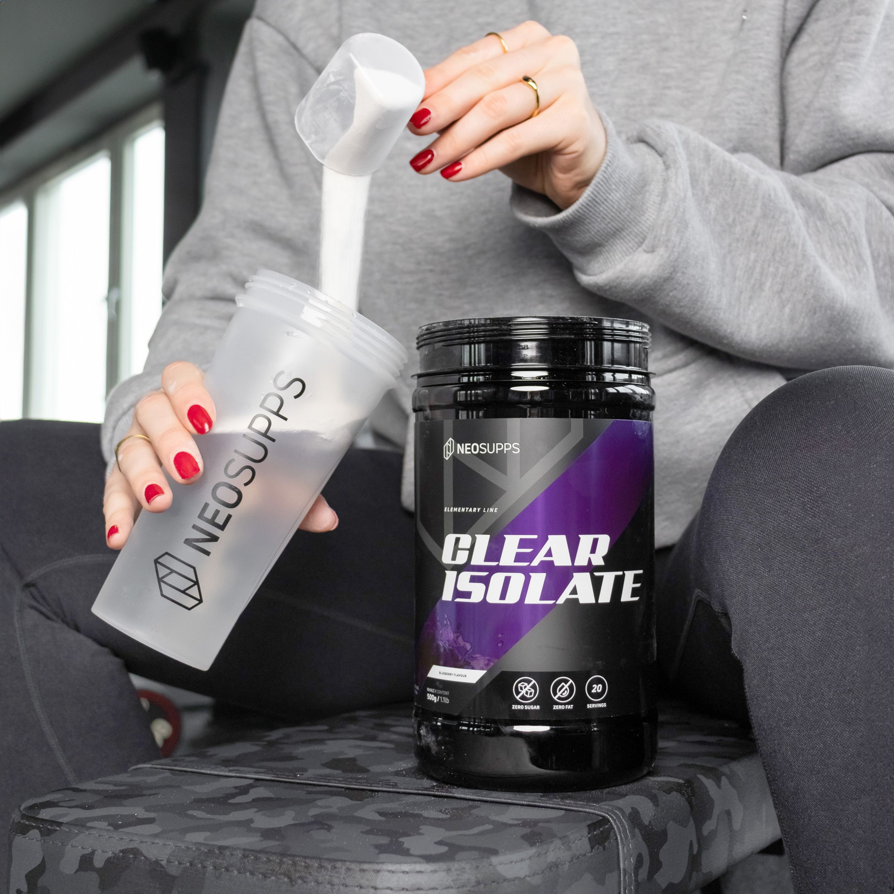 Person gießt Pulver aus einem Shaker in eine Dose. Dose mit Aufschrift: CLEAR ISOLATE.