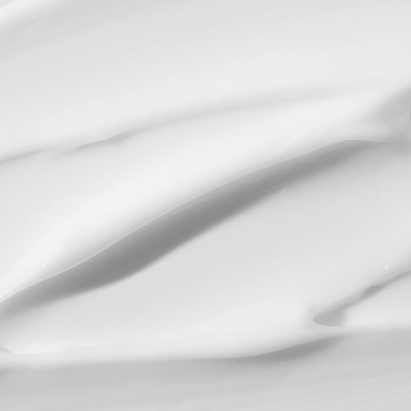 Nahaufnahme von weißer Creme-Oberfläche. Glatte Textur mit Schatten. Keine Beschriftung sichtbar.