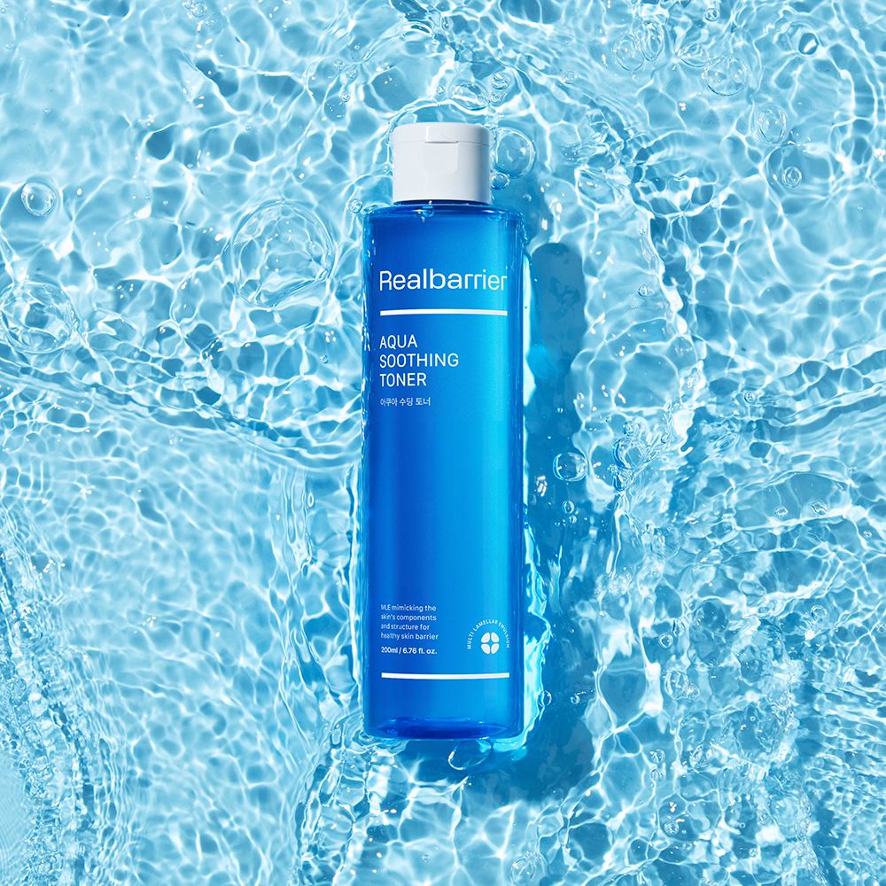 Blaues Toner-Fläschchen in Wasser. Aufschrift: Realbarrier, Aqua Soothing Toner. Weißer Deckel. Wasser mit Blasen.