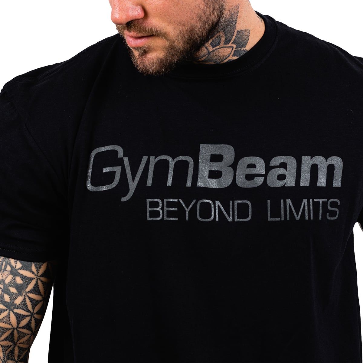 Nahaufnahme des schwarzen GymBeam T-Shirts mit dem "BEYOND LIMITS" Logo auf der Brust.