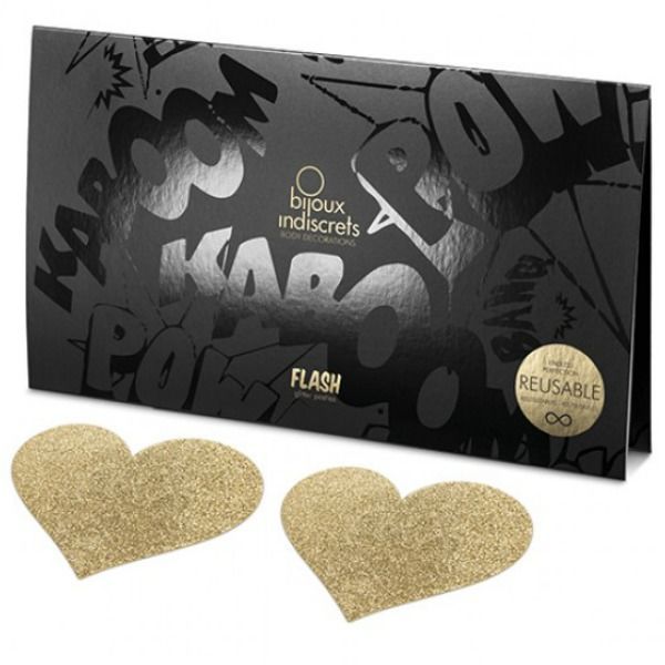 Zwei goldfarbene, herzförmige Nippelcover mit Glitzer neben einer geöffneten schwarzen Verpackung. Aufdruck: Bijoux Indiscrets.