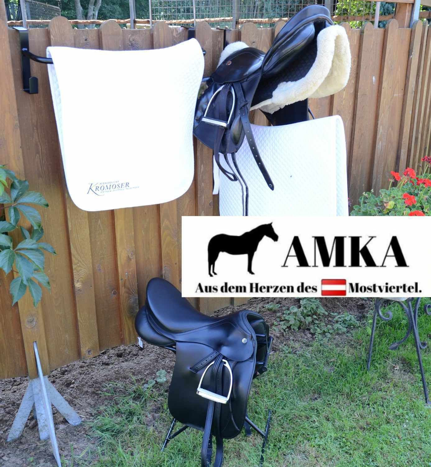 Sättel und Decken auf einem Zaun. Logo: AMKA, Aus dem Herzen des Mostviertel.