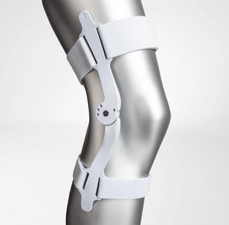 Weiße Kniebandage mit Scharnieren und Klettverschlüssen. Das Produkt ist an einem Bein angebracht.