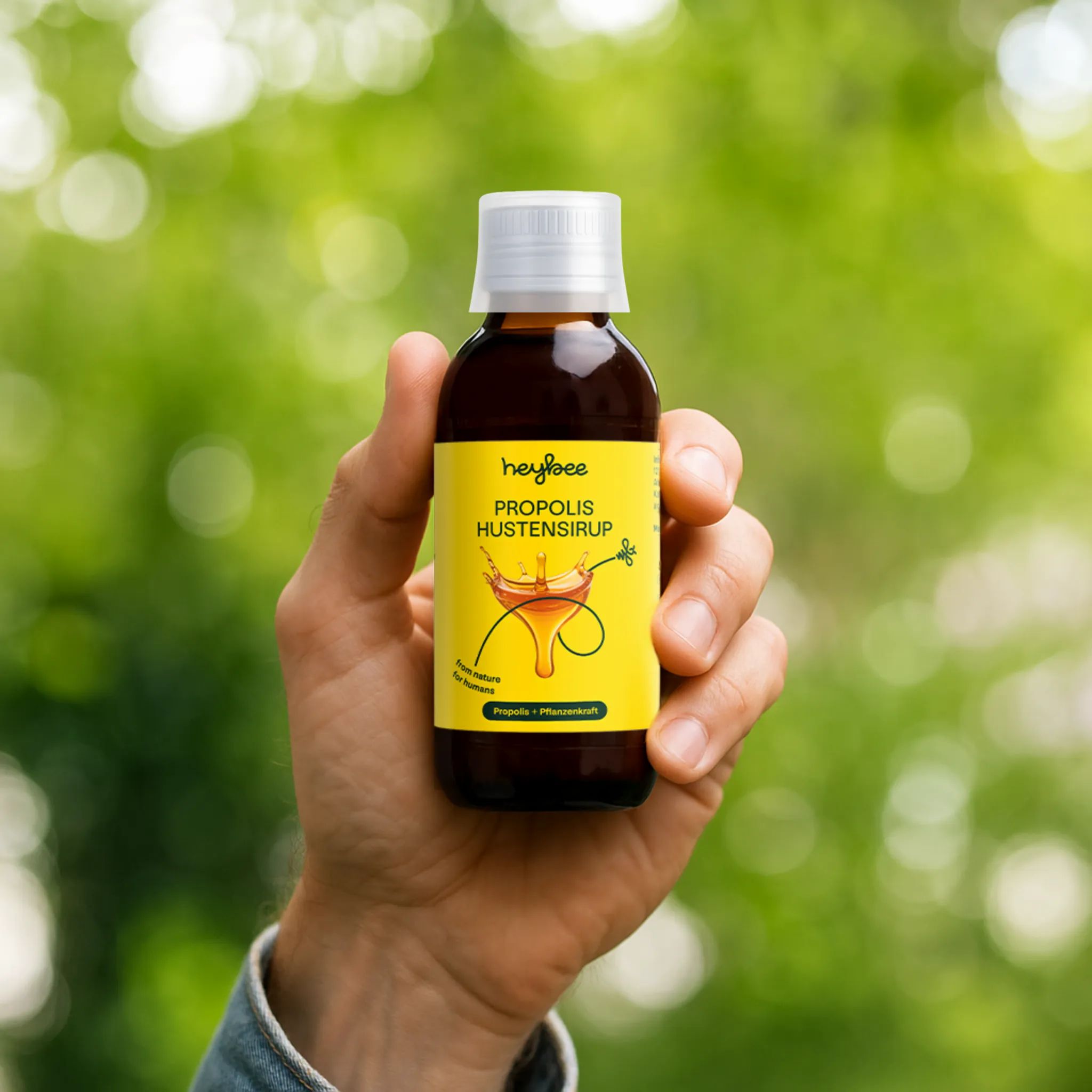 Hand hält Flasche Heybee Propolis Hustensirup. Text: Propolis Hustensirup. Für Husten. Gelbes Etikett mit Produktinformationen.