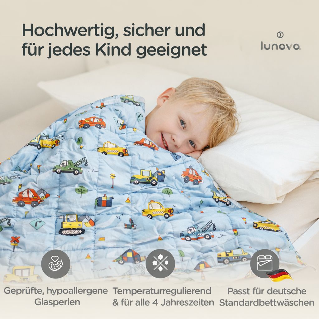 Eine Junge schläft unter einer blauen Gewichtsdecke mit Fahrzeugmotiven. Die Decke fördert die Melatoninproduktion.