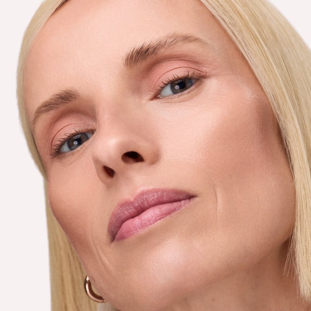 Nahaufnahme eines Gesichts mit rosa Lidschatten. Blonde Haare, helle Haut. Blick nach unten.