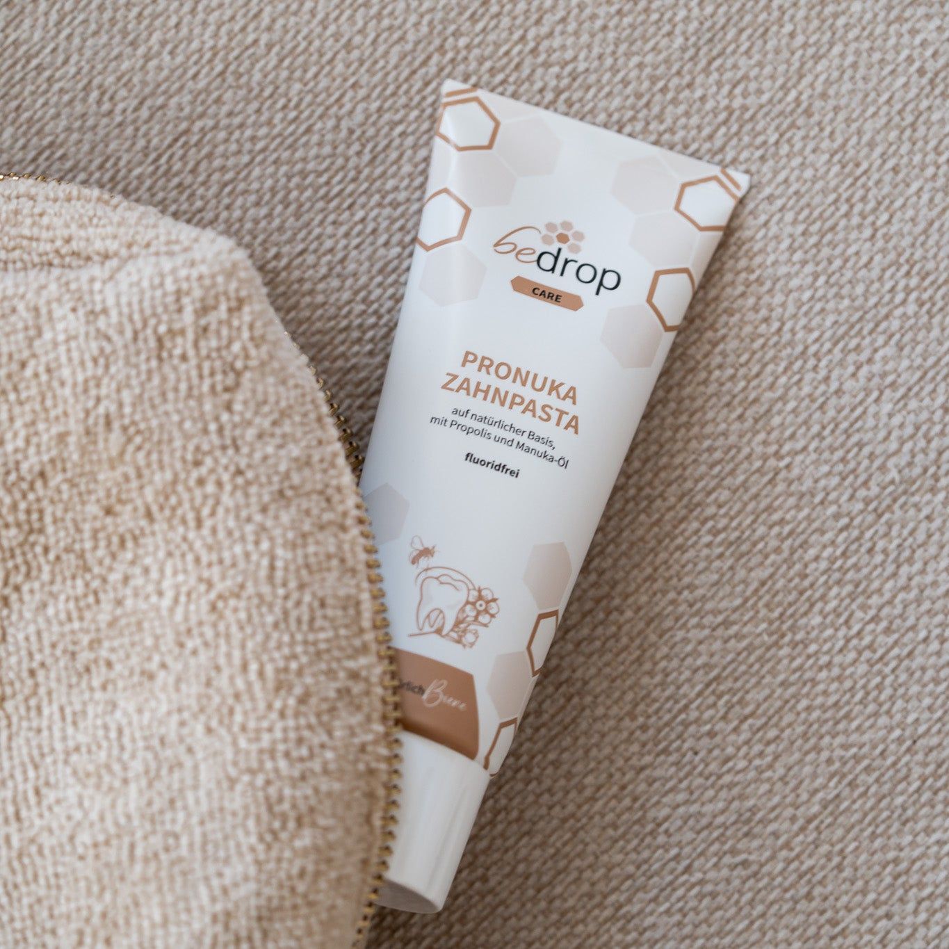 Tube bedrop Pronuka Zahnpasta in einer beigen Tasche. Tube weiß mit braunen Akzenten und Produktinformationen. Aufschrift: Pronuka Zahnpasta, fluoridfrei.