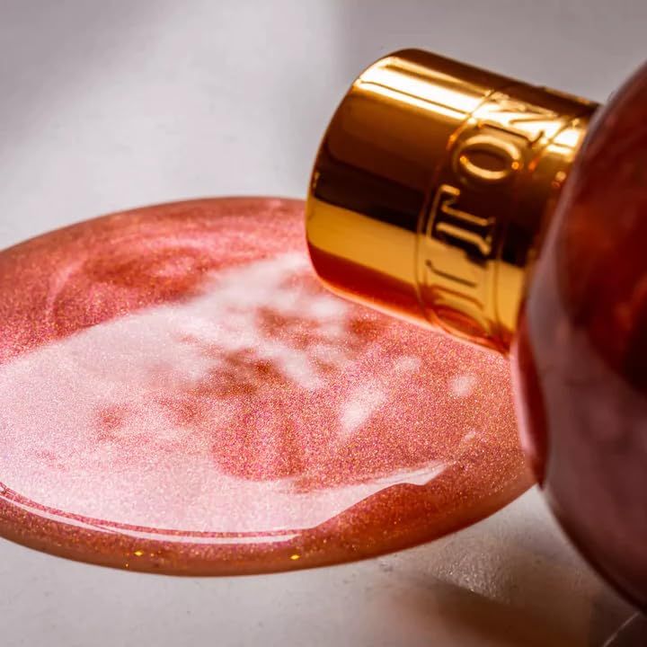 Duschgel von Molton Brown, Rose Dunes, liegt auf einer Oberfläche. Goldener Deckel, rosa Flüssigkeit.