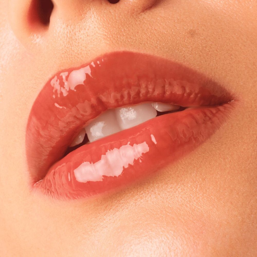 Nahaufnahme von Lippen mit glänzendem Lipgloss. Farbe: orange-braun. Lippen sind leicht geöffnet.