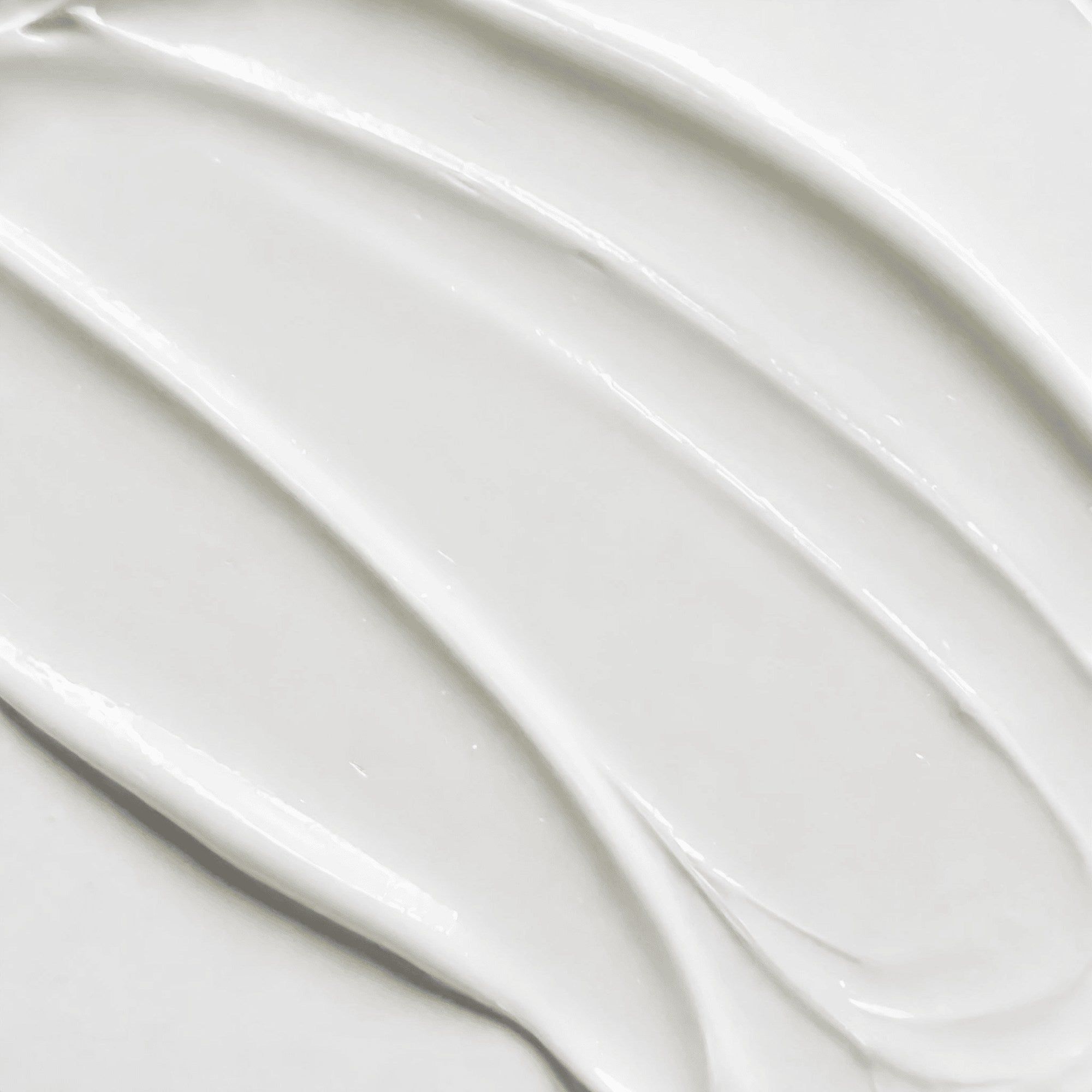 Nahaufnahme von weißer Creme. Glatte, gewellte Textur, diagonal angeordnet.