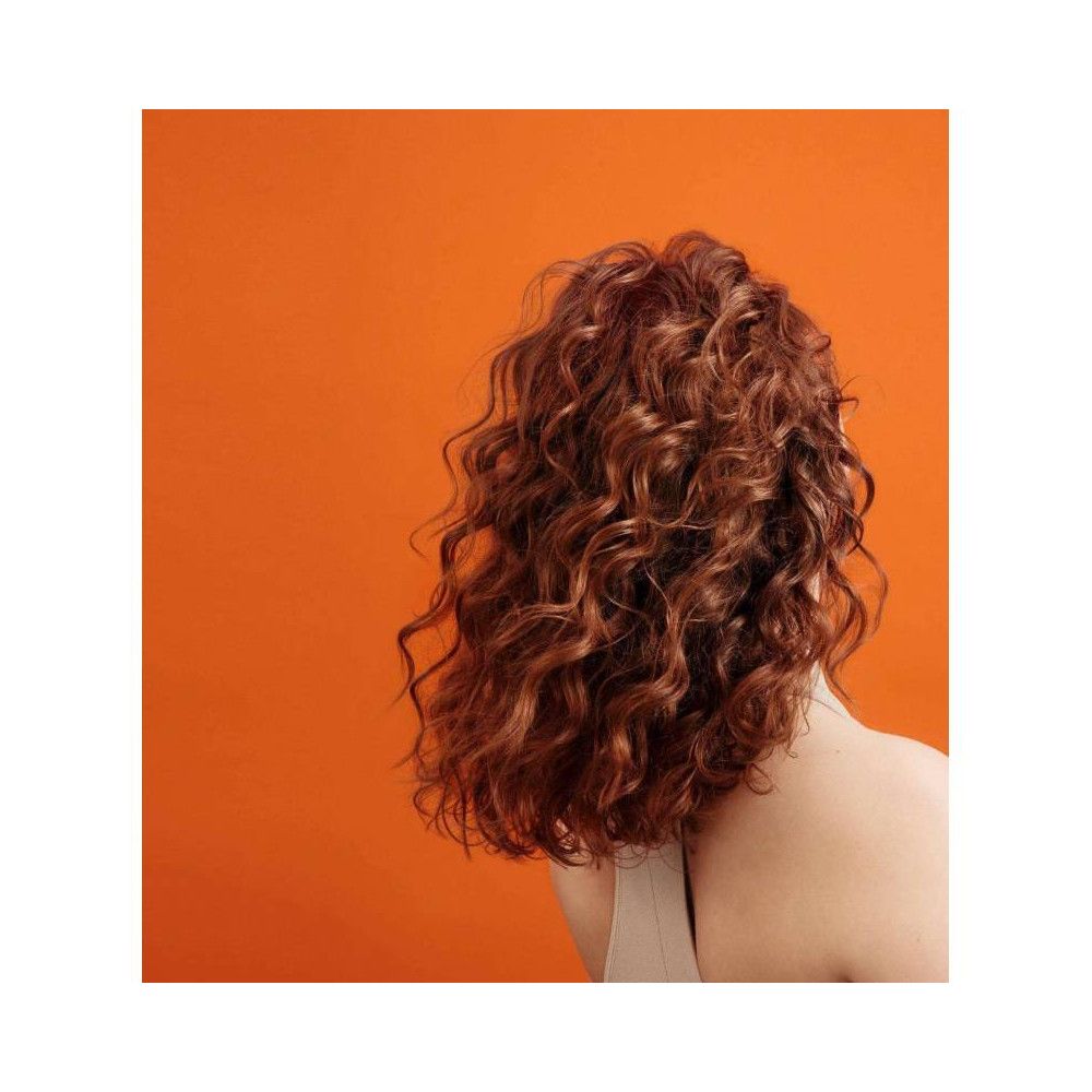 Rückansicht einer Person mit lockigem, rotem Haar. Hintergrund orange.