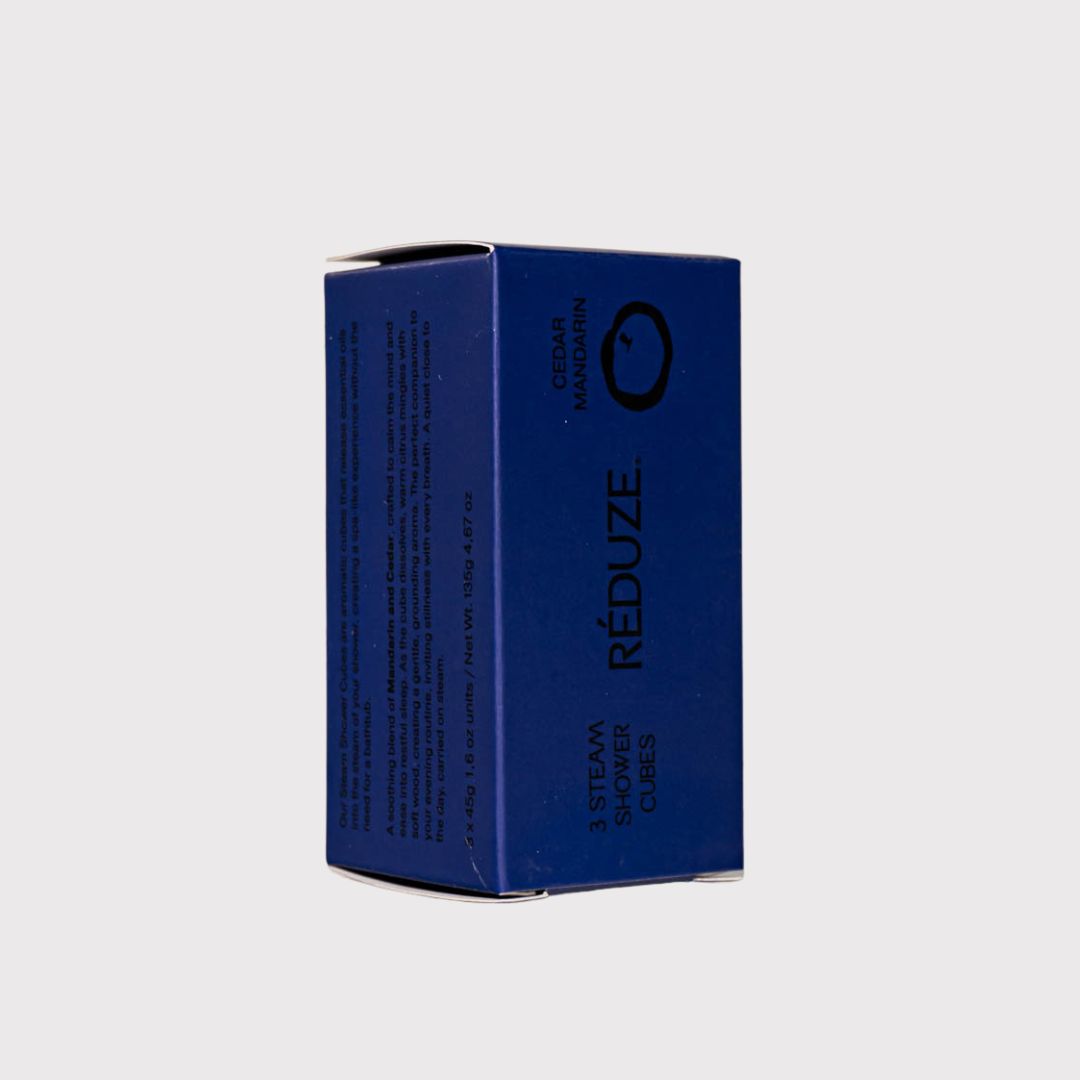Blaue Schachtel mit Produktinformationen. RÉDUZE. Zedernholz & Mandarine. 3 Steam Shower Cubes. Seitenansicht.