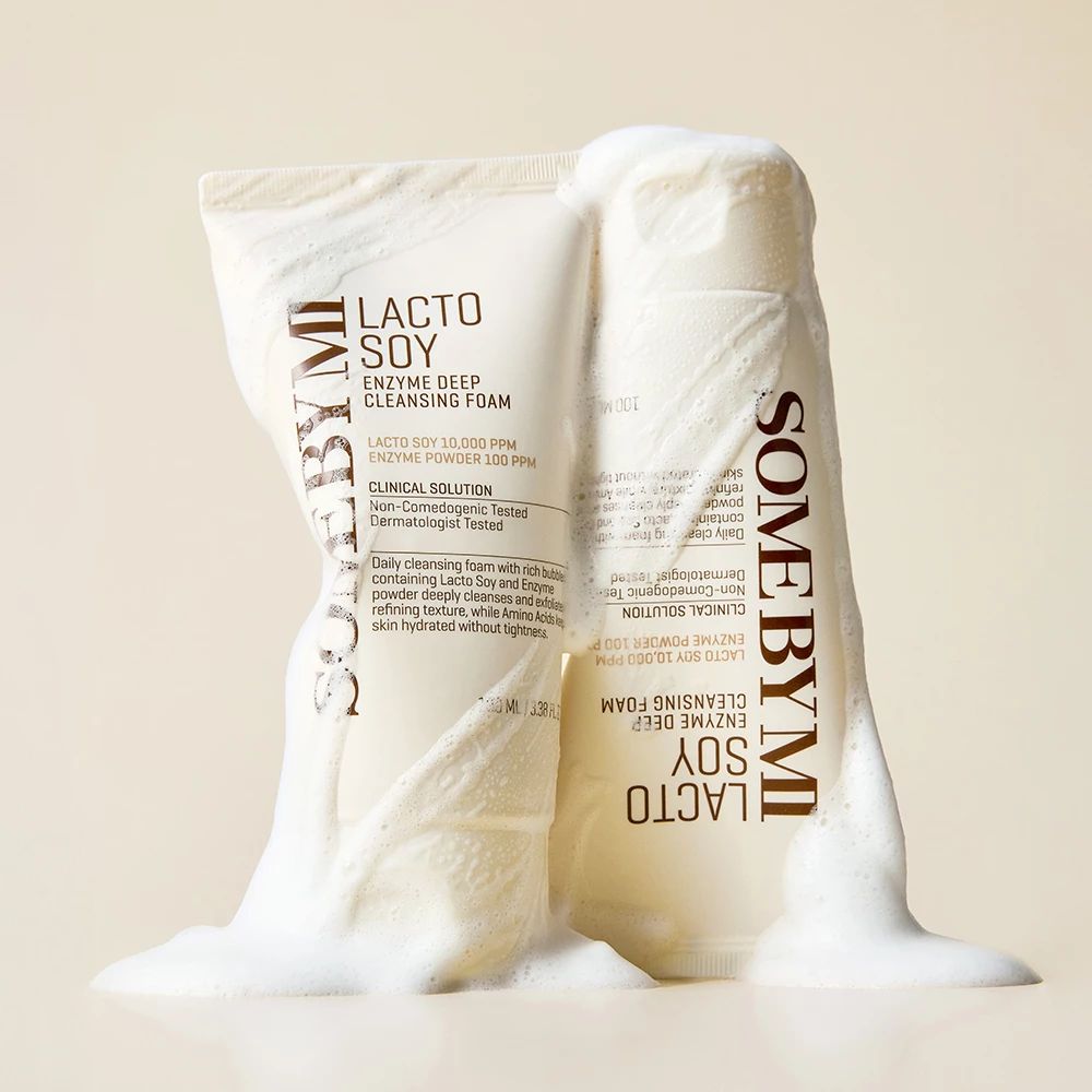 Zwei Tuben mit weißem Reinigungsschaum, bedeckt mit Schaum. Auf den Tuben steht "Lacto Soy Enzyme Deep Cleansing Foam".