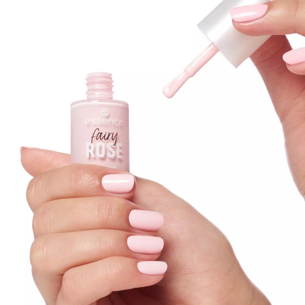 Hand mit lackierten Nägeln in Rosa. Nagellackflasche und Pinsel sichtbar.