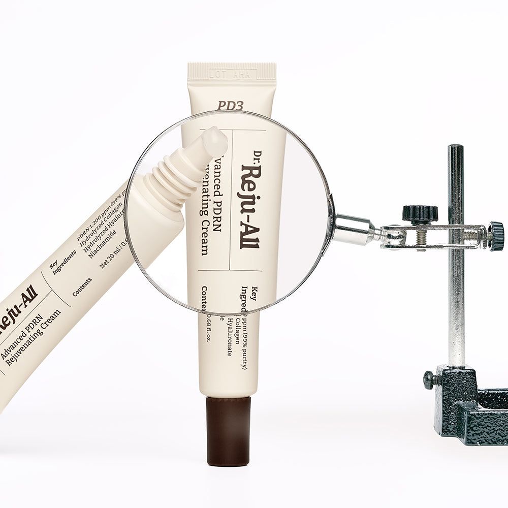 Lupe über einer Tube Dr. Reju-All Advanced PDRN Rejuvenating Cream, die den Text auf der Tube hervorhebt.