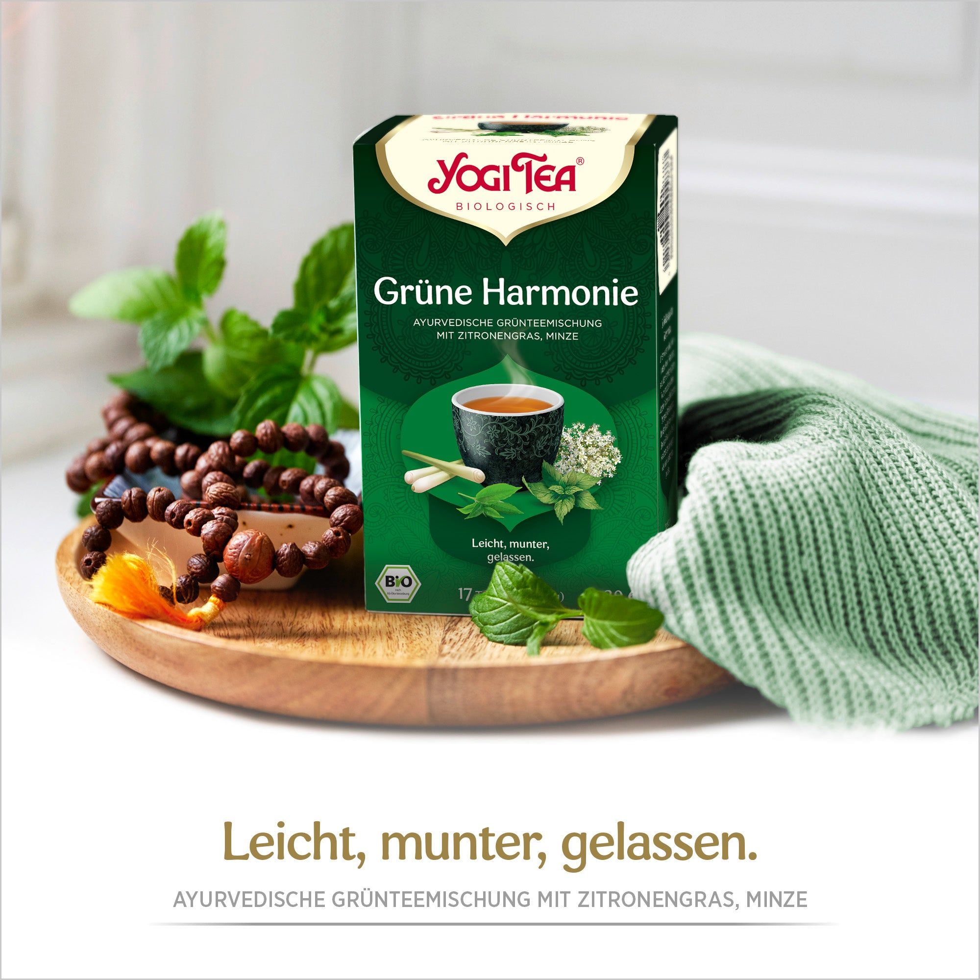Grüne Tee-Schachtel, Yogi Tea, Grüne Harmonie, Bio. Aufdruck: 17 Teebeutel. Auf Holzbrett, mit Kräutern und Schmuck.